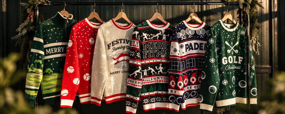 Six festive Christmas sweaters in different designs and colors hang on wooden hangers against a dark wooden door with holiday greenery. The sweaters include green with 'MERRY', red with baseball motifs, cream with 'FESTIVAL HUNTER', multicolor with reindeer and 'MERRY', navy with 'PADE' and sports motifs, and green with 'GOLF Christmas' text.